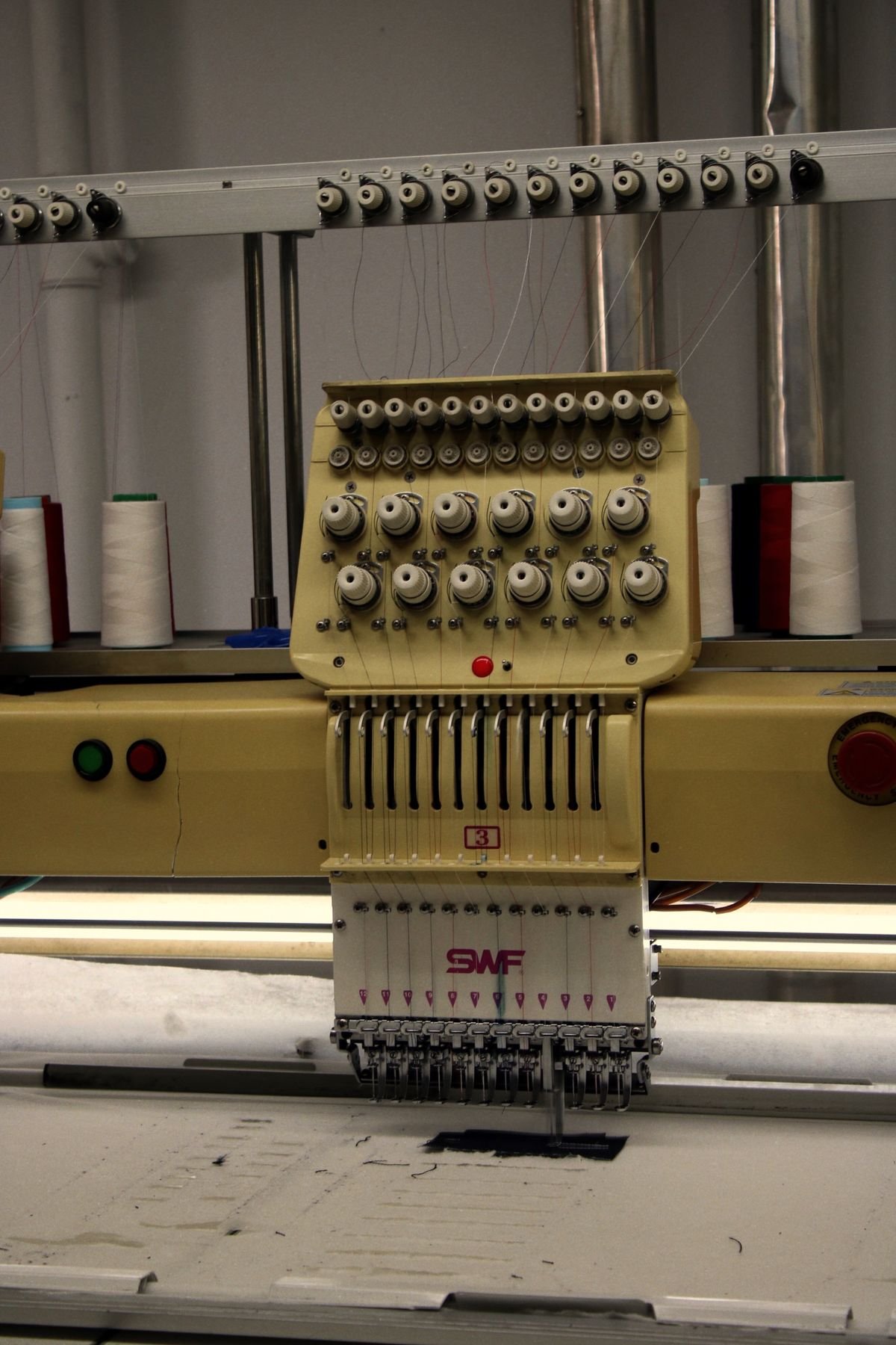 Representative photo of a multi-needle embroidery machine with thread cones in operation