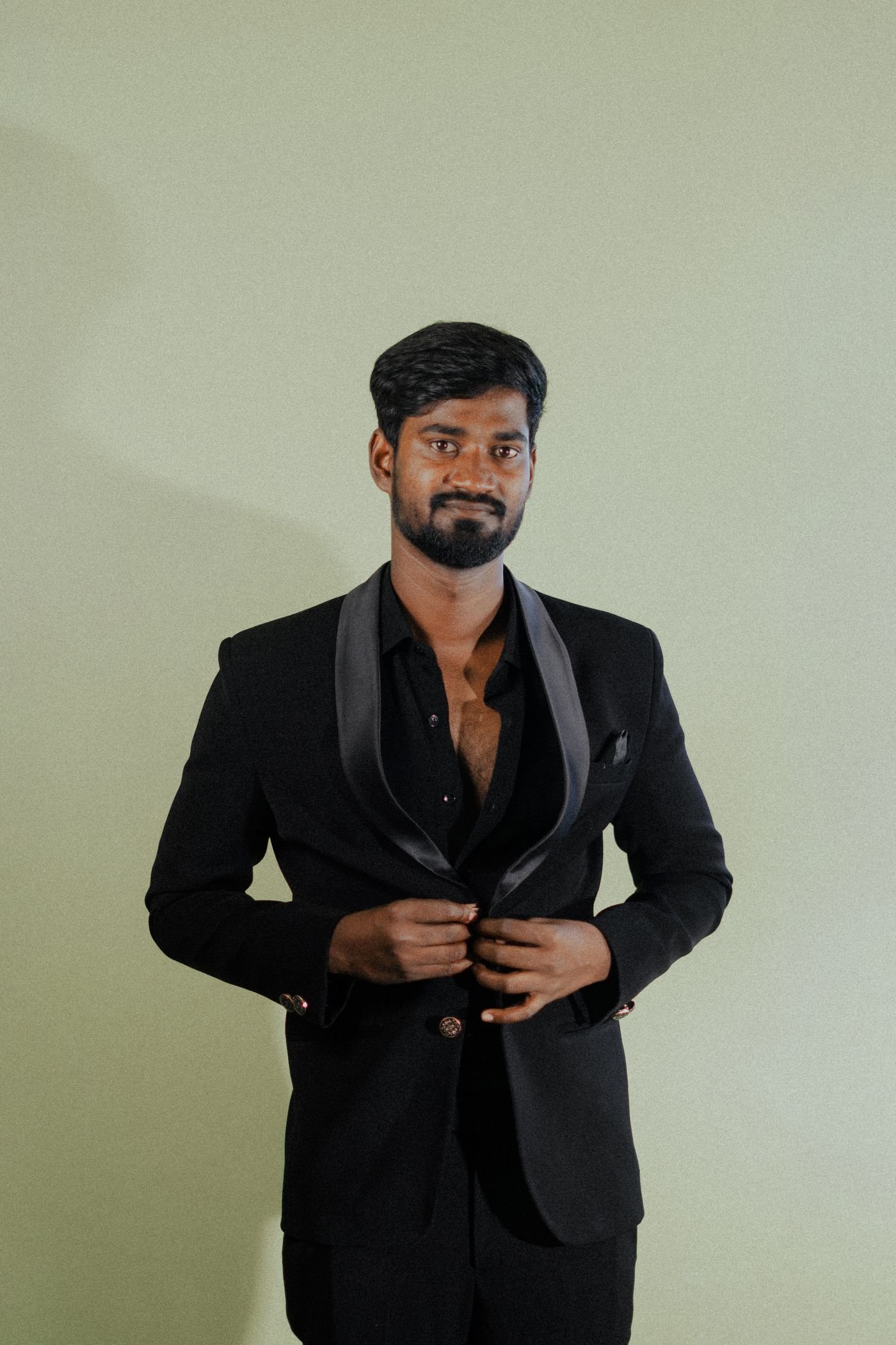 Representative photo of a man in a tailored black formal suit buttoning the jacket