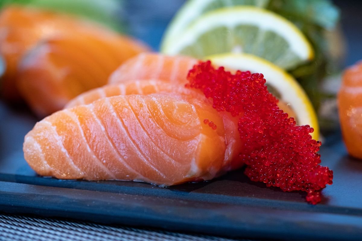 Representative photo: fresh salmon fillet with roe and citrus on a dark board.