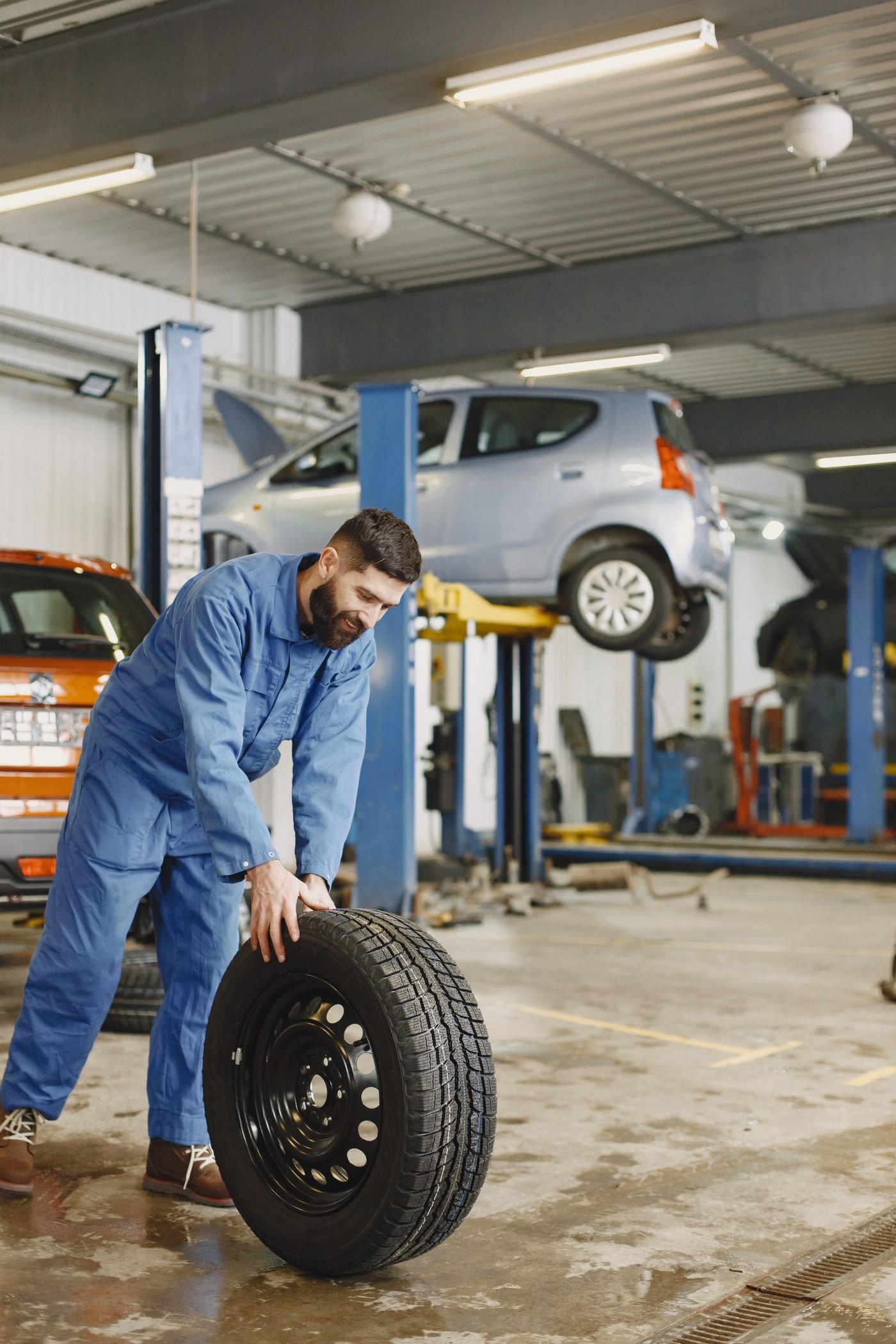 Representative photo of a tire technician rolling a tire across the floor of a service bay
