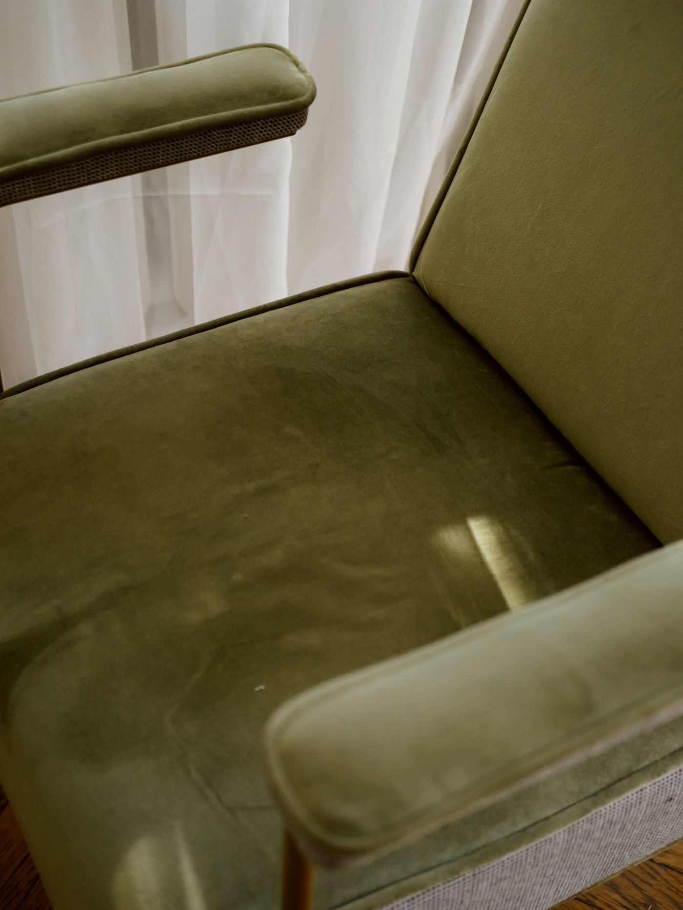Representative close-up of an olive-green velvet chair seat and arm, showing the upholstered finish