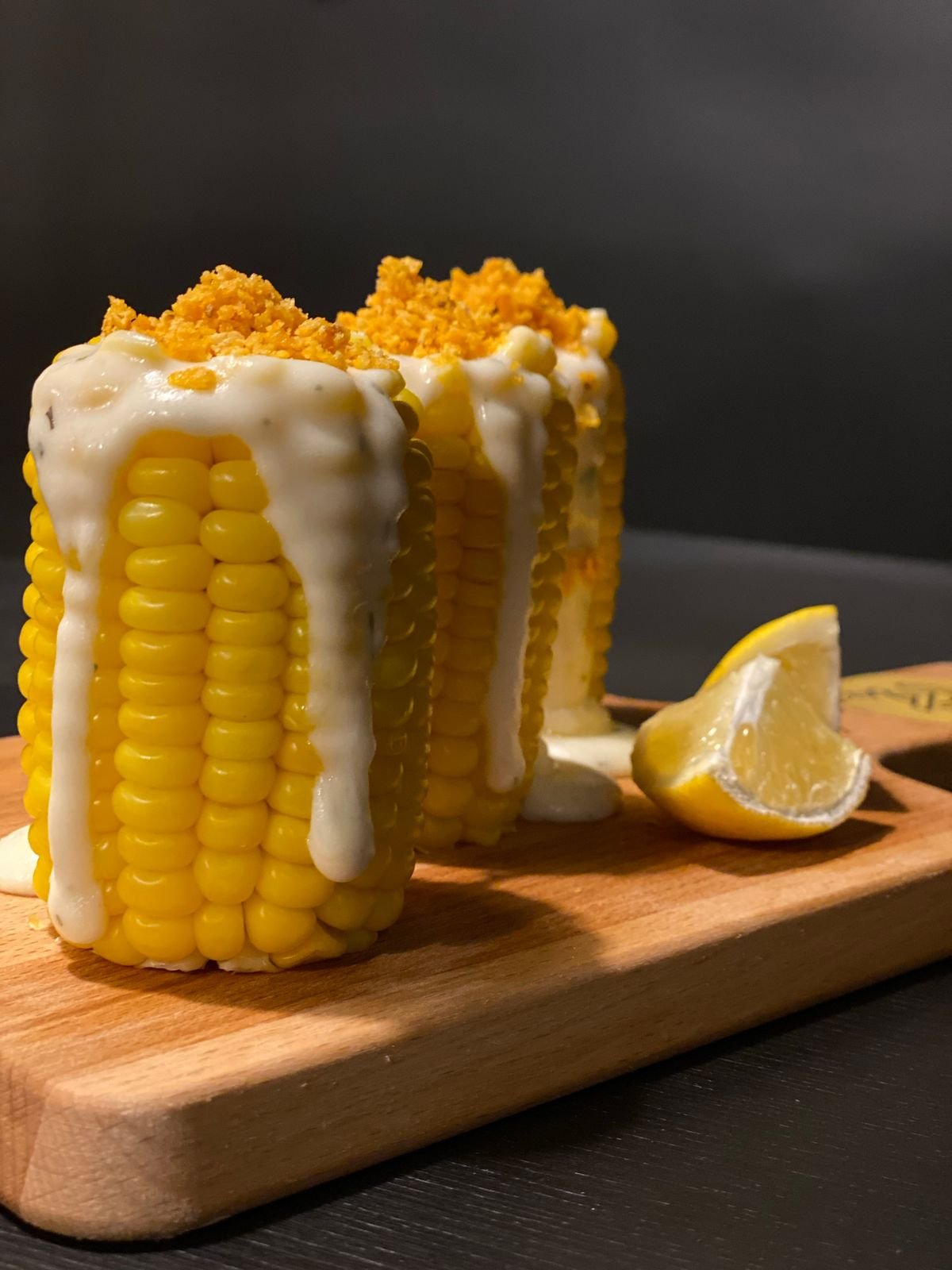 Representative photo of grilled corn cobbettes loaded with creamy sauce and cheese crumble