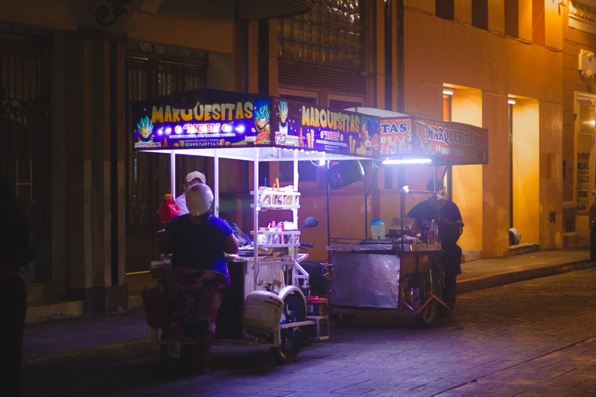 Representative photo of a Mexican street-food cart lit up in the evening