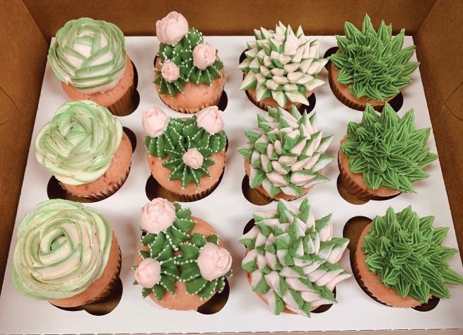A dozen cupcakes hand-piped with succulent-style buttercream in greens and blush