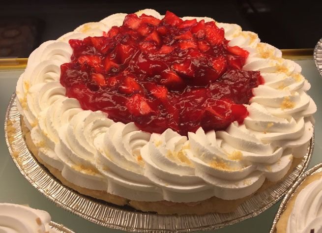 Fresh strawberry cream pie topped with piped whipped cream