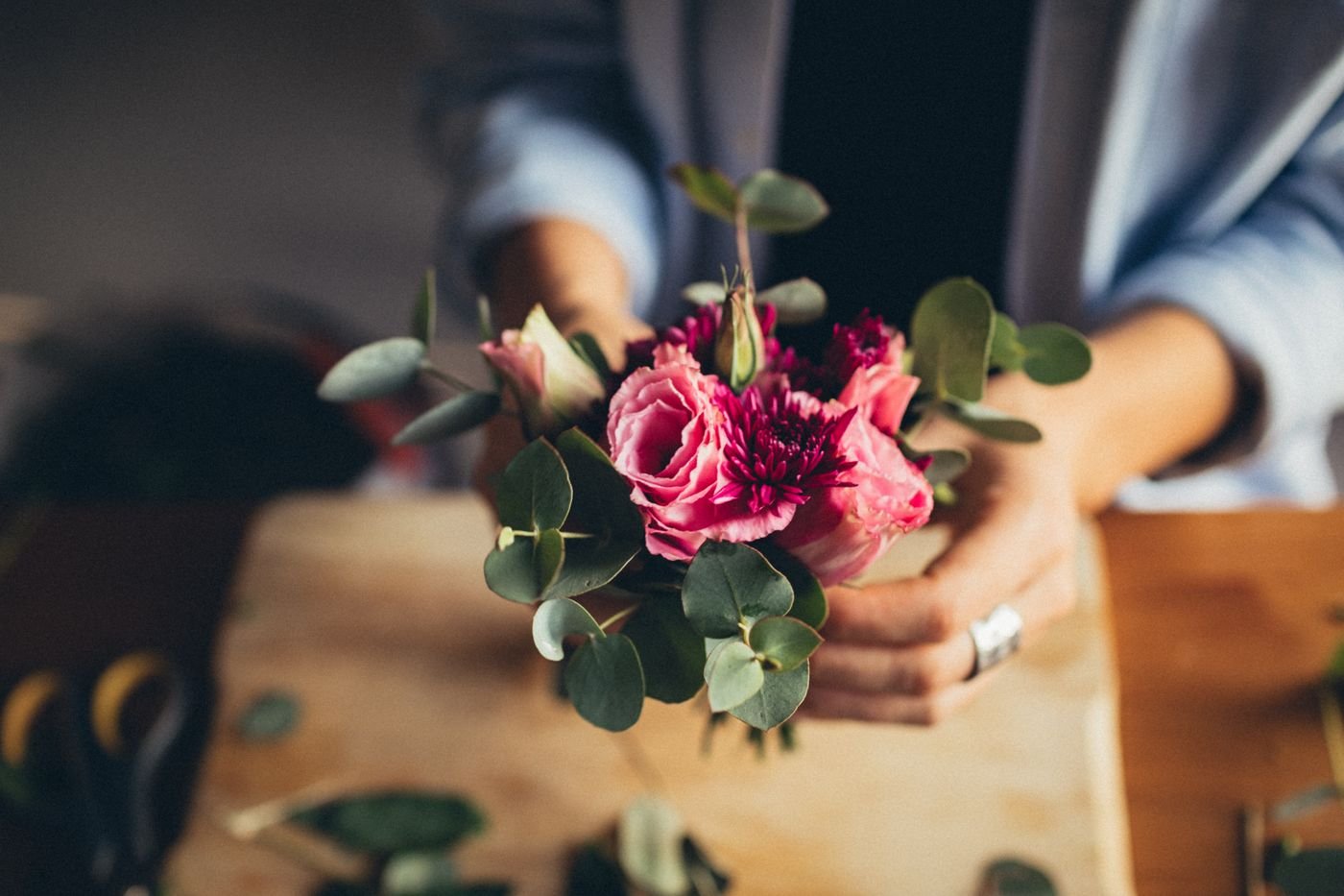 Representative photo of a florist arranging a small bouquet of pink roses.