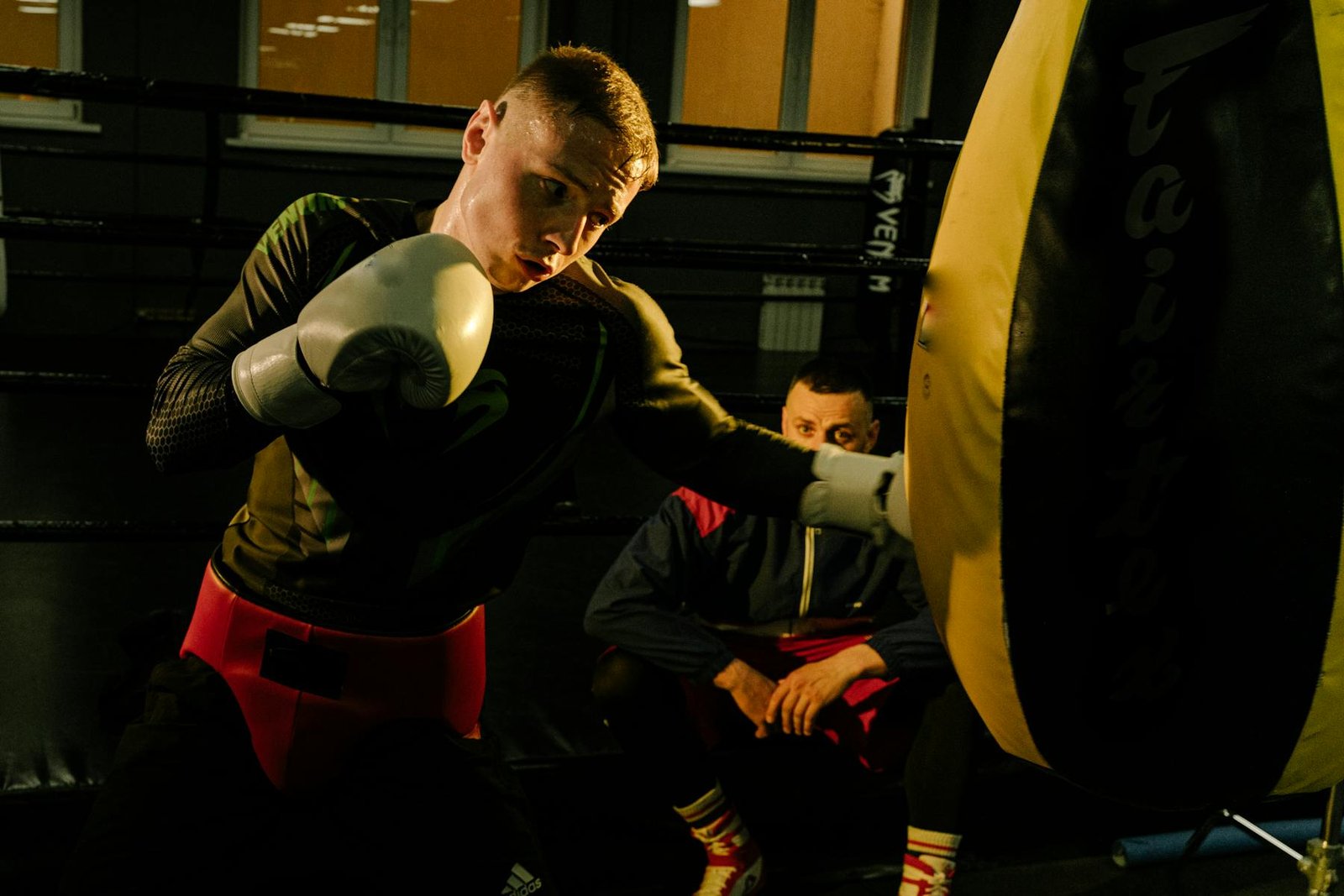 Boxing coach watching a heavy bag training round
