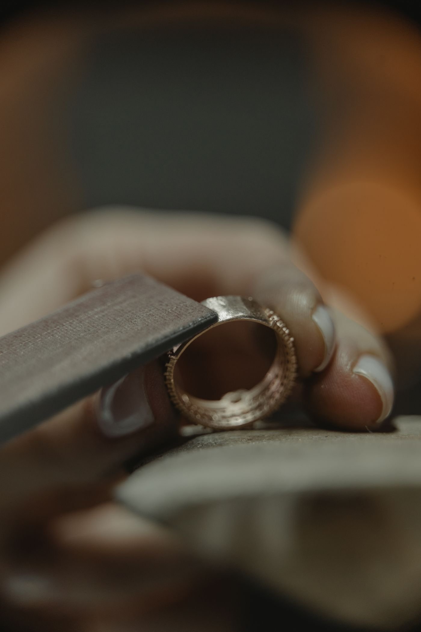 A jeweler finishing a gold ring by hand at the workbench — representative of on-site bench work