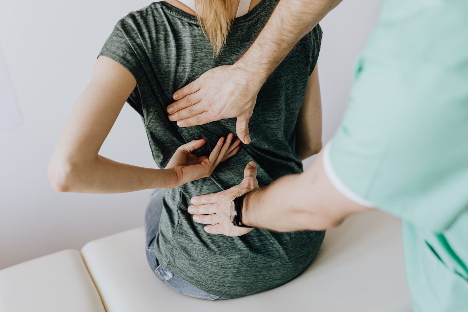 Representative photo of a chiropractor assessing a patient's back by hand to locate the source of pain