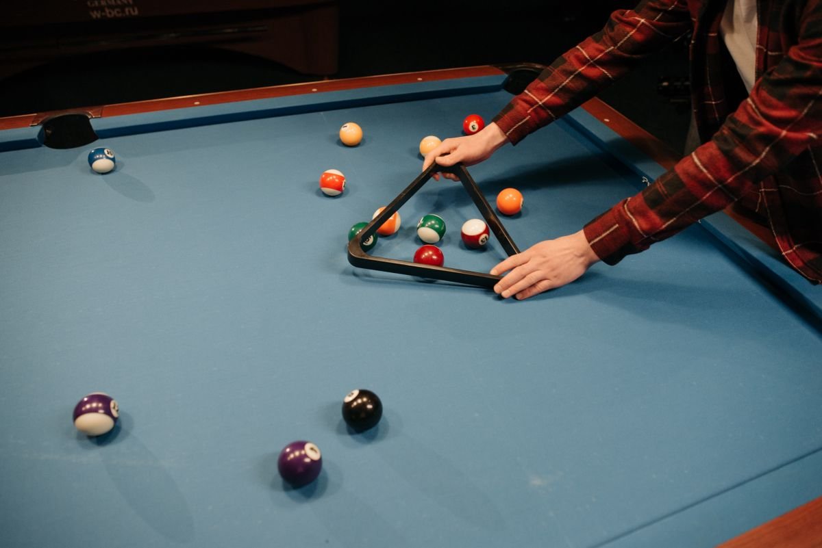 Representative photo of billiard balls being racked on a blue pool table