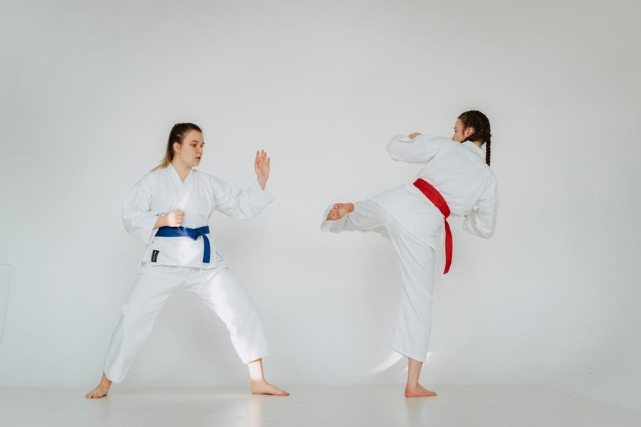 Representative photo of two adults in white karate uniforms practicing a kick and block