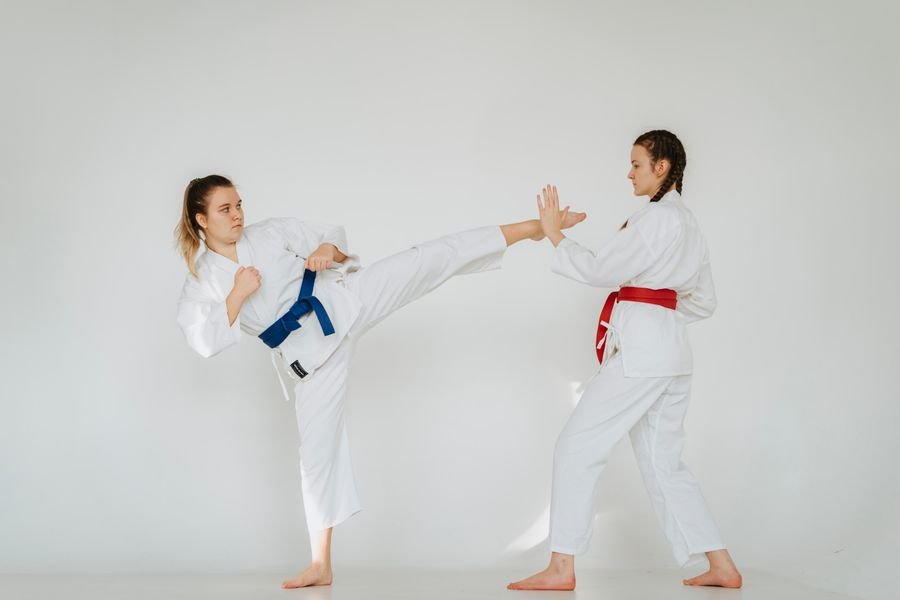 Representative photo of two people drilling a self-defense kick and palm block in karate uniforms